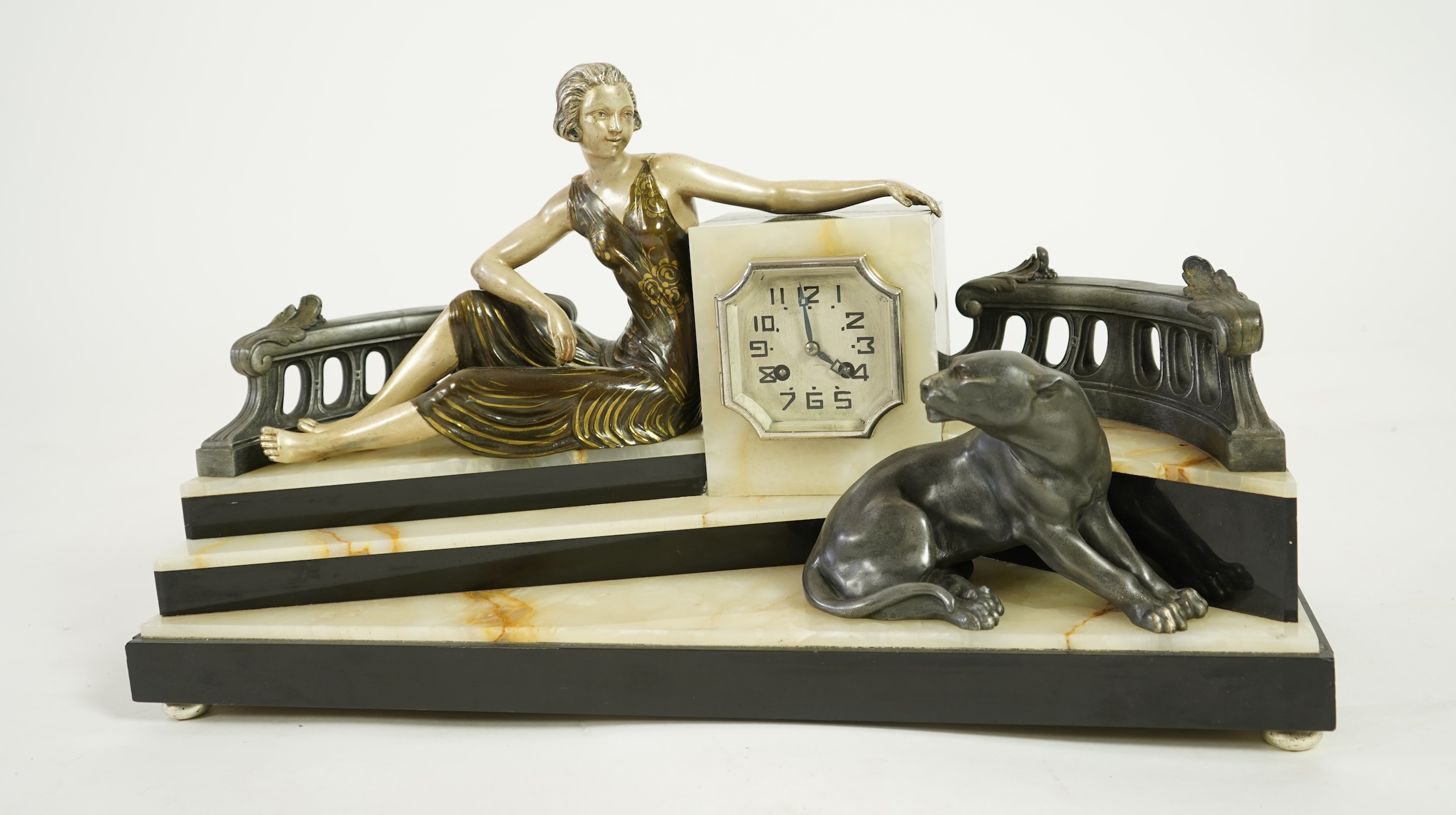 A French Art Deco onyx and patinated spelter clock surmounted with a lady and a black panther on a staircase